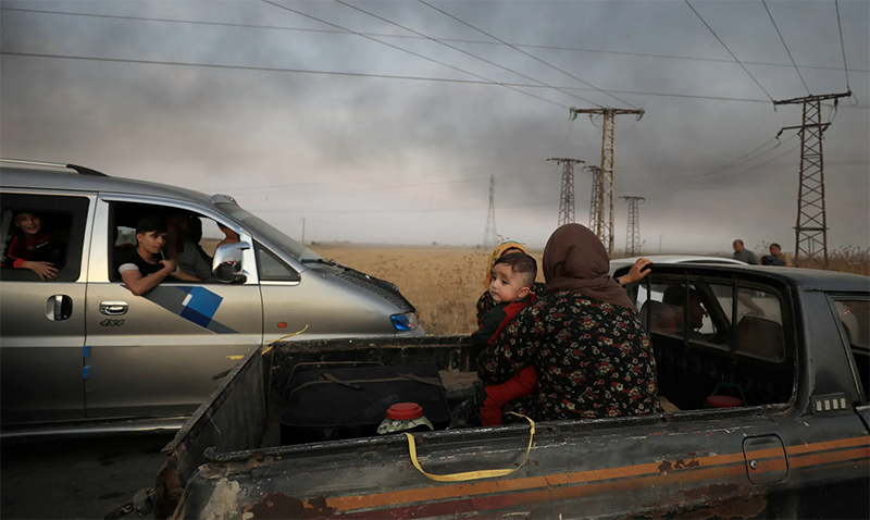 ⬆︎ una donna con un bambino fugge da Ras al-Ain dopo che la Turchia ha lanciato un assalto all&rsquo;area controllata dai Curdi nel nordest della Siria. Foto di Rodi Said / Reuters